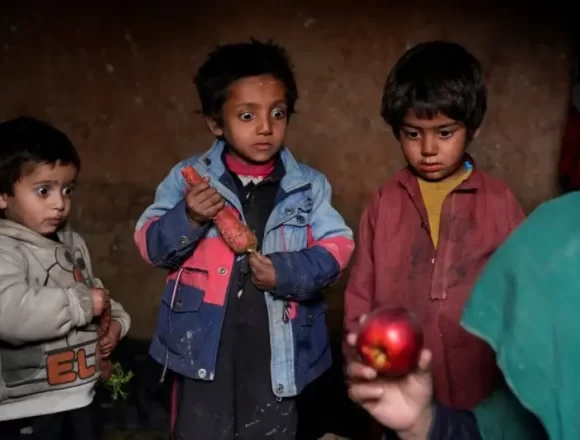 Афганские дети смотрят на яблоко, которое их мать принесла домой после того, как просила милостыню в лагере для беженцев на окраине Кабула